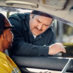Agente de trânsito conversa com o motorista pela janela de um carro durante uma abordagem.