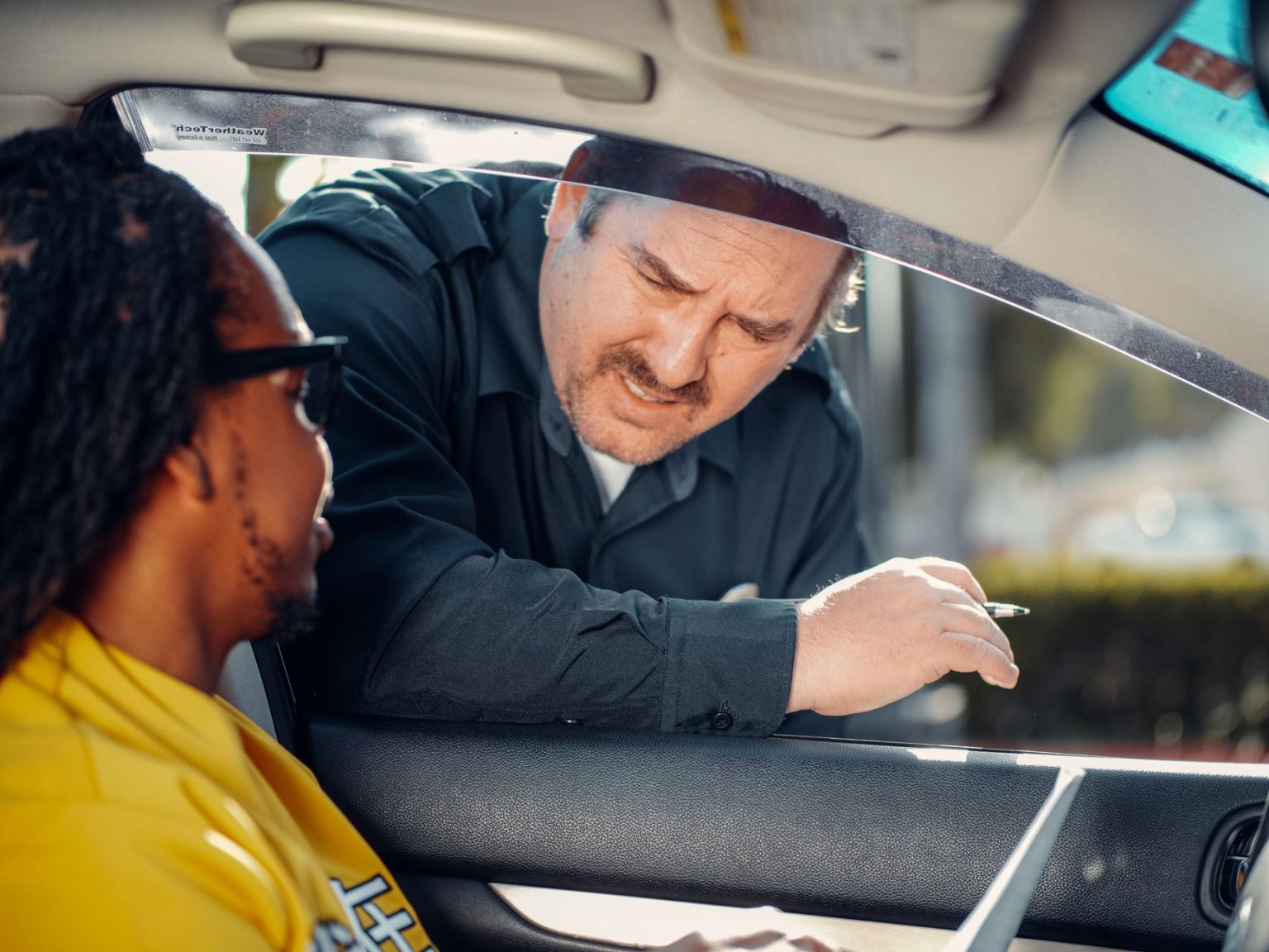 Agente de trânsito conversa com o motorista pela janela de um carro durante uma abordagem.