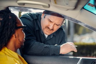 Agente de trânsito conversa com o motorista pela janela de um carro durante uma abordagem.