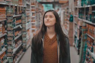 Mulher observa produtos nas prateleiras de um supermercado.
