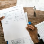 Mãos analisam documentos financeiros relacionados à preparação e revisão tributária.