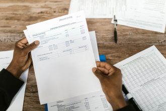 Mãos analisam documentos financeiros relacionados à preparação e revisão tributária.